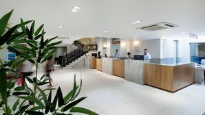 A modern reception area with a staircase, reception desk, and a large potted plant. - Hotel Miramar (Balneário Camboriú)