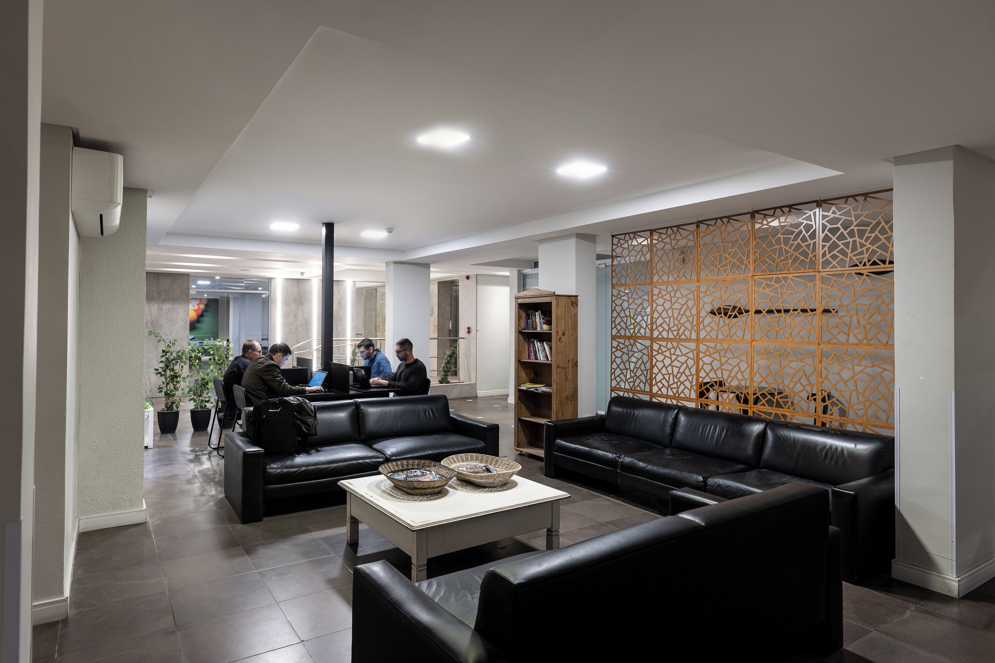 A modern lobby with leather sofas, a coffee table, and a decorative wooden partition.