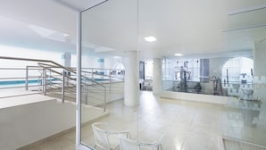 A modern indoor swimming pool area with glass walls, a staircase, and exercise equipment. - Hotel Miramar (Balneário Camboriú)