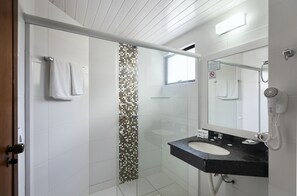 A modern bathroom with a glass-enclosed shower, a white sink with a black countertop, and a large mirror.
