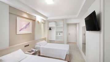 Habitación de hotel con dos camas, televisión, un cuadro y vestidor.