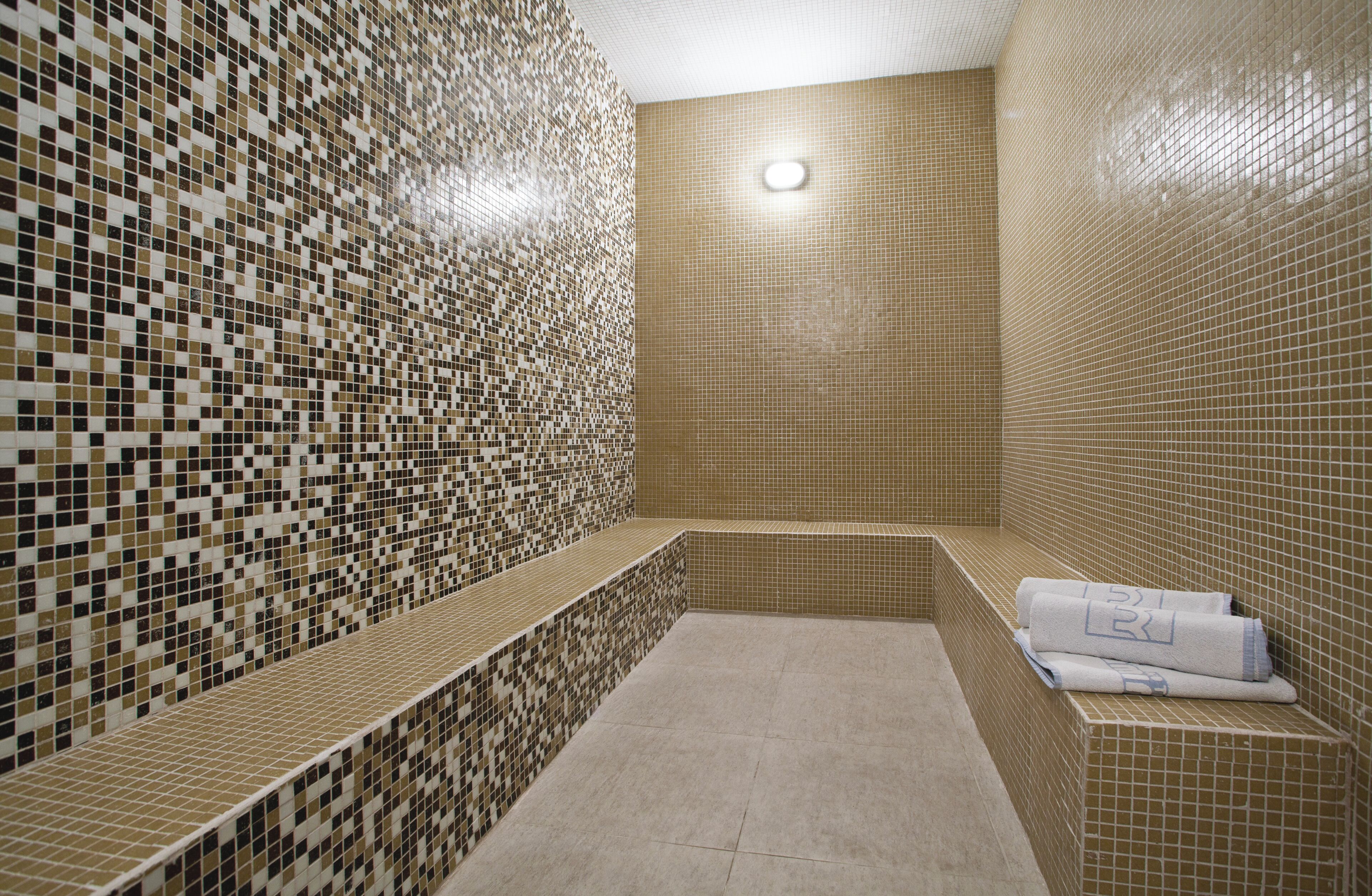 Casa de banho com azulejos, um banco e toalhas.