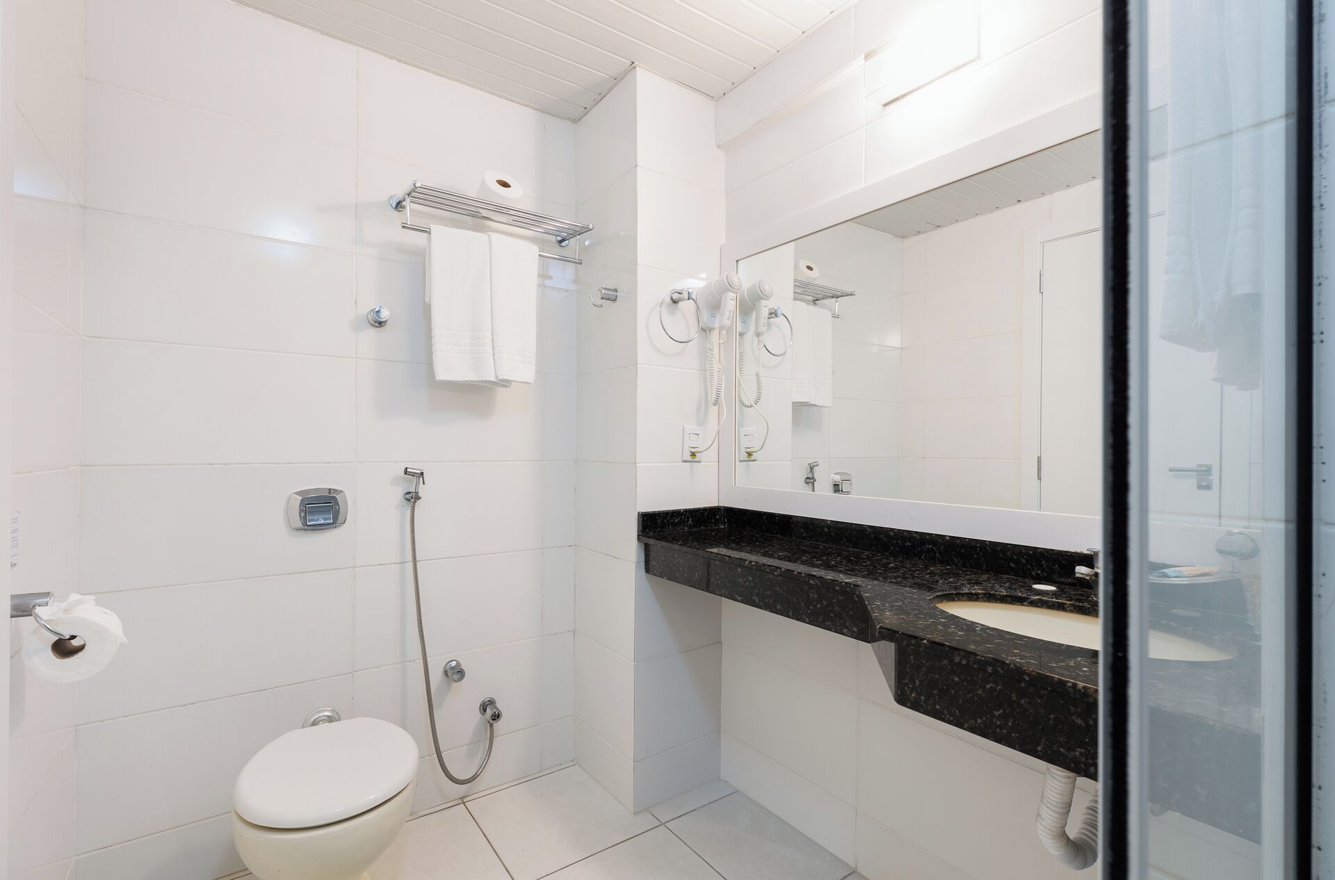 Un baño moderno con inodoro, ducha, lavamanos y un espejo grande.