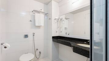 Un baño moderno con inodoro, ducha, lavamanos y un espejo grande.