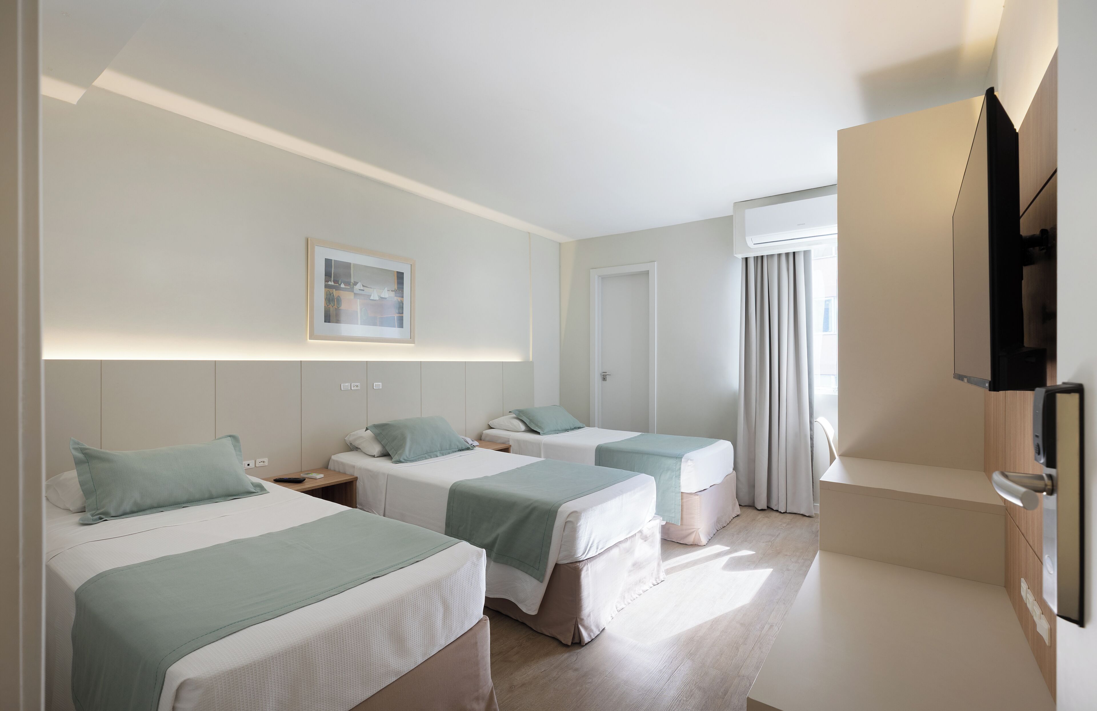 Quarto de hotel com duas camas, televisão, um quadro e janela com cortinas.