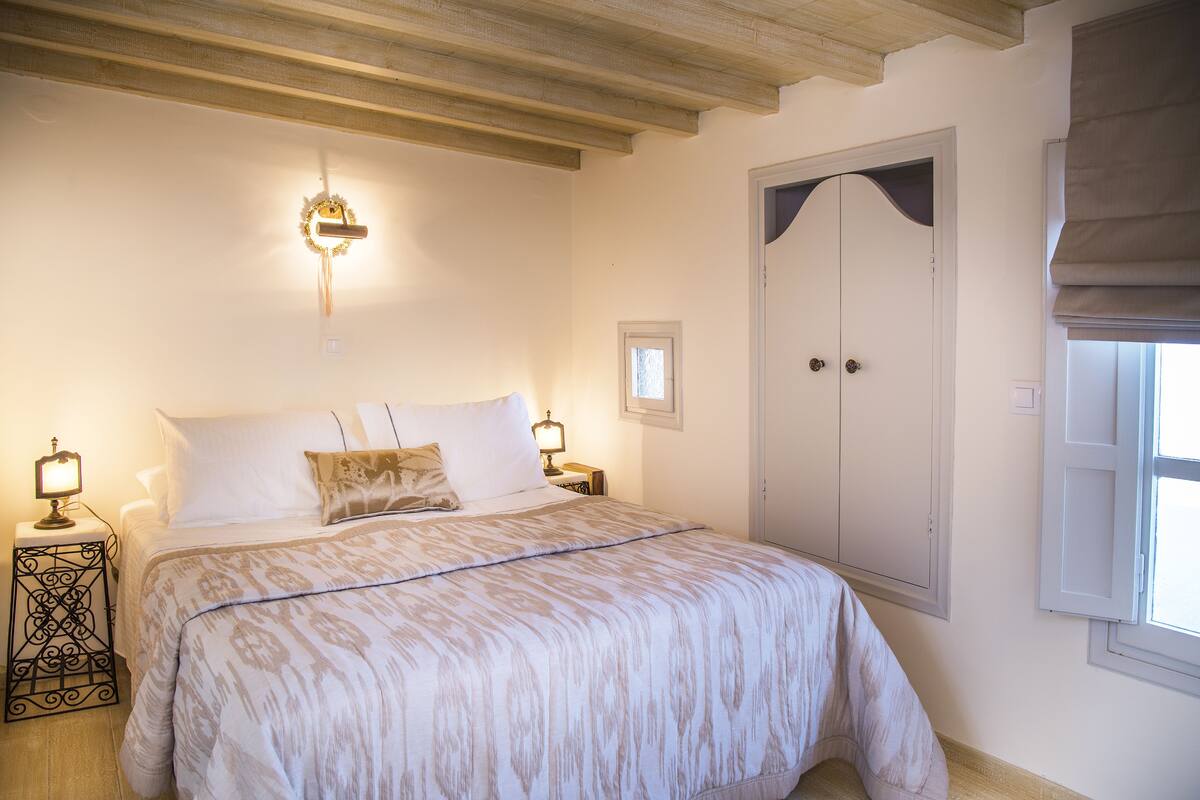 Een slaapkamer met een bed, nachtlampjes, een kledingkast en een raam met een blind.