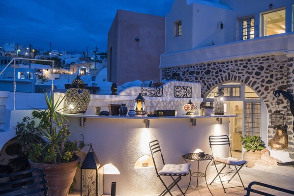 A rooftop terrace with a bar, seating, and potted plants.