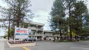 Un motel avec un panneau indicateur, un parking et un bâtiment à plusieurs étages doté de balcons.