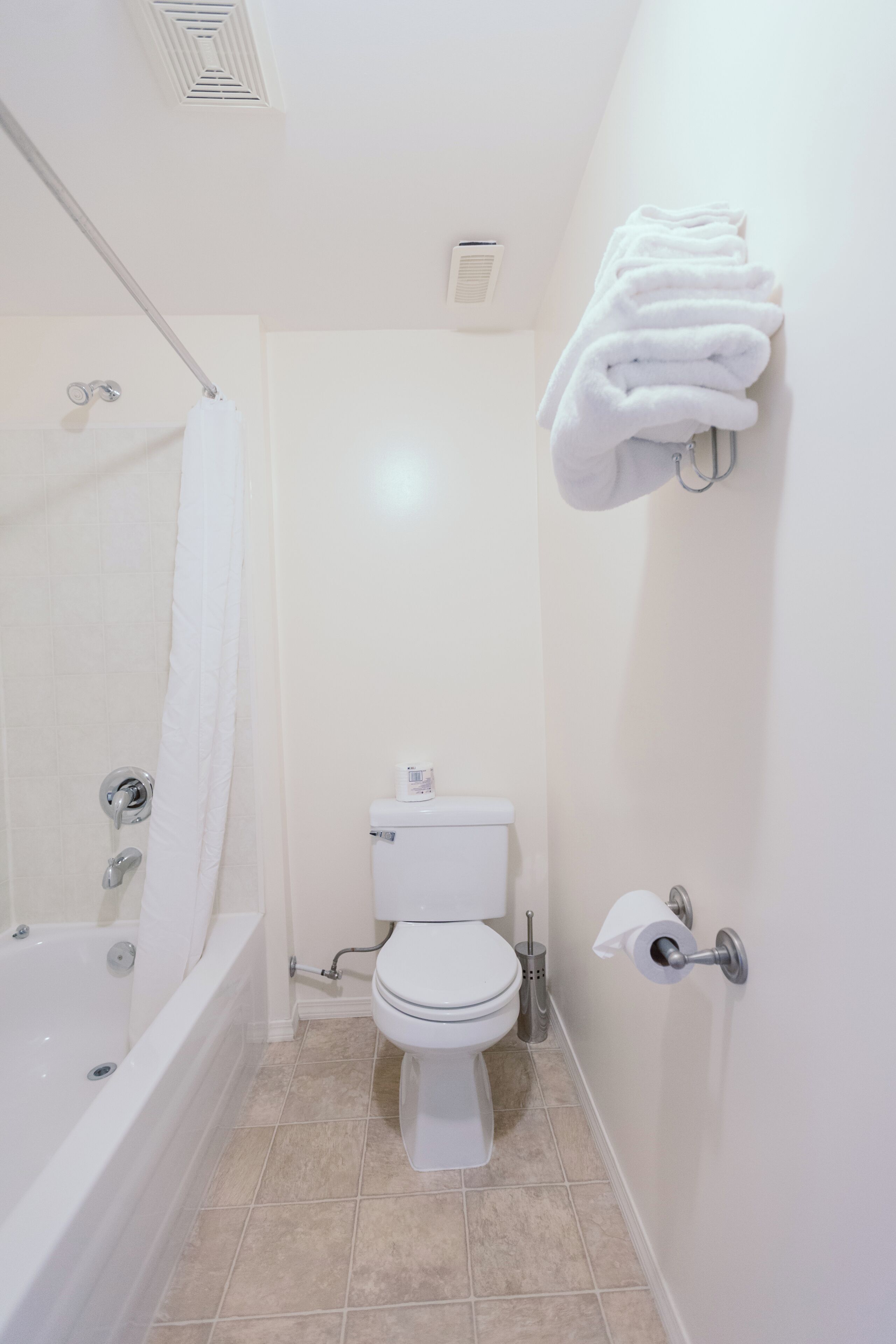 A bathroom with a bathtub, toilet, and a towel rack.