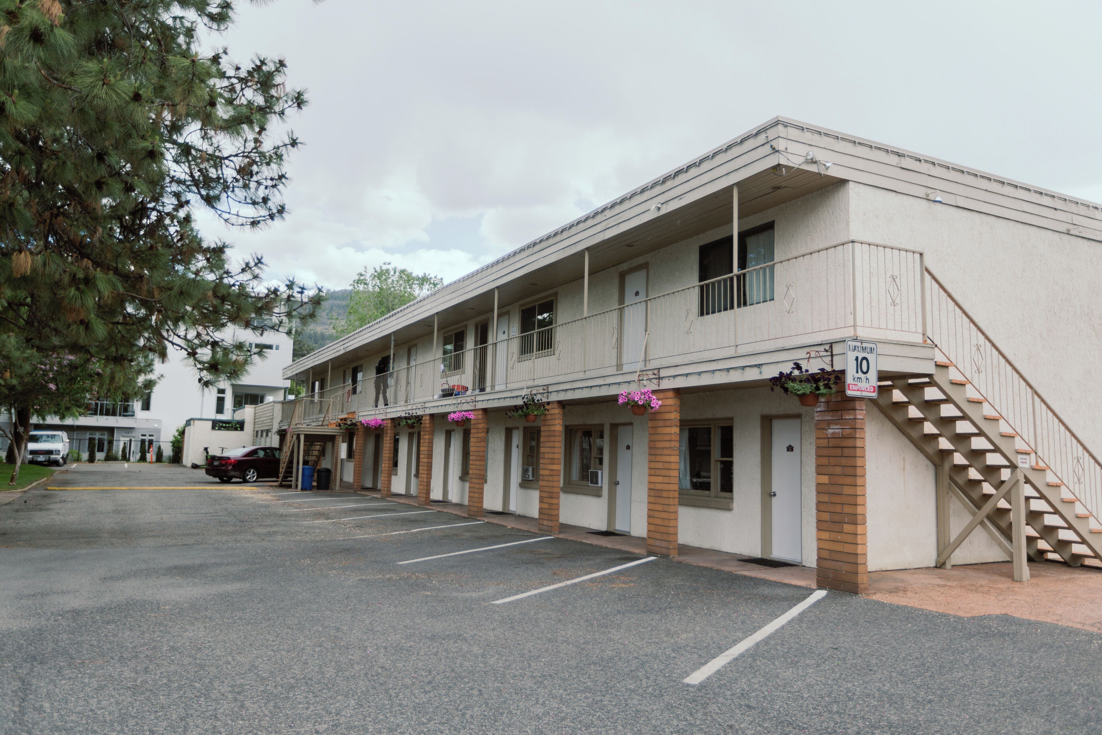 A motel with a two-story structure, a parking lot, and a staircase leading to the upper floor.