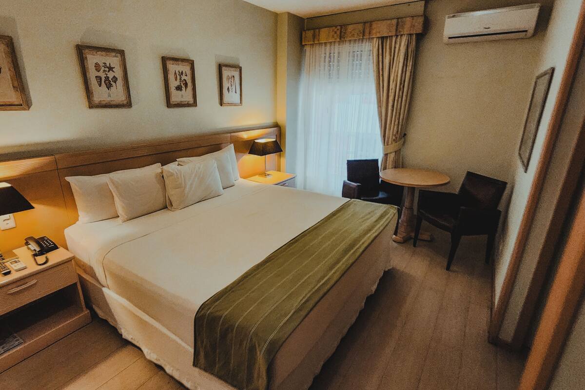 Una habitación de hotel con una cama grande, mesitas de noche, un escritorio y una silla.