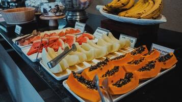 Buffet com diversas frutas e um letreiro mostrando o preço da mamão.