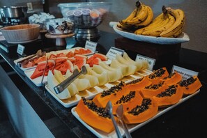 Een buffet met diverse soorten fruit en een bord dat de prijs van papaya aangeeft.