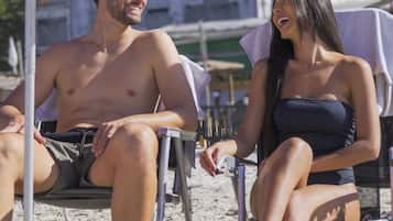 Una playa cerca, arena blanca, sillas reclinables de playa, sombrillas