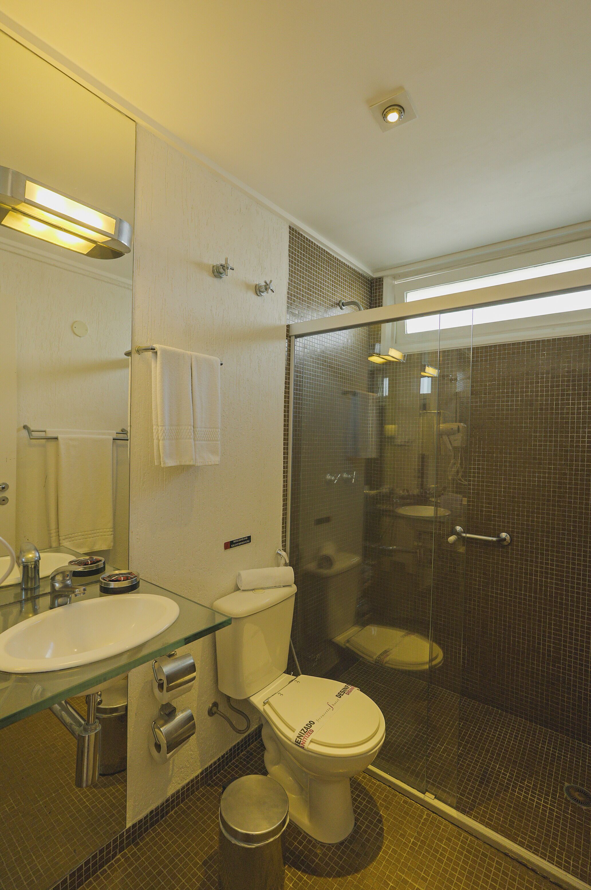 Une salle de bain avec une douche à parois de verre, un lavabo en verre et des toilettes.