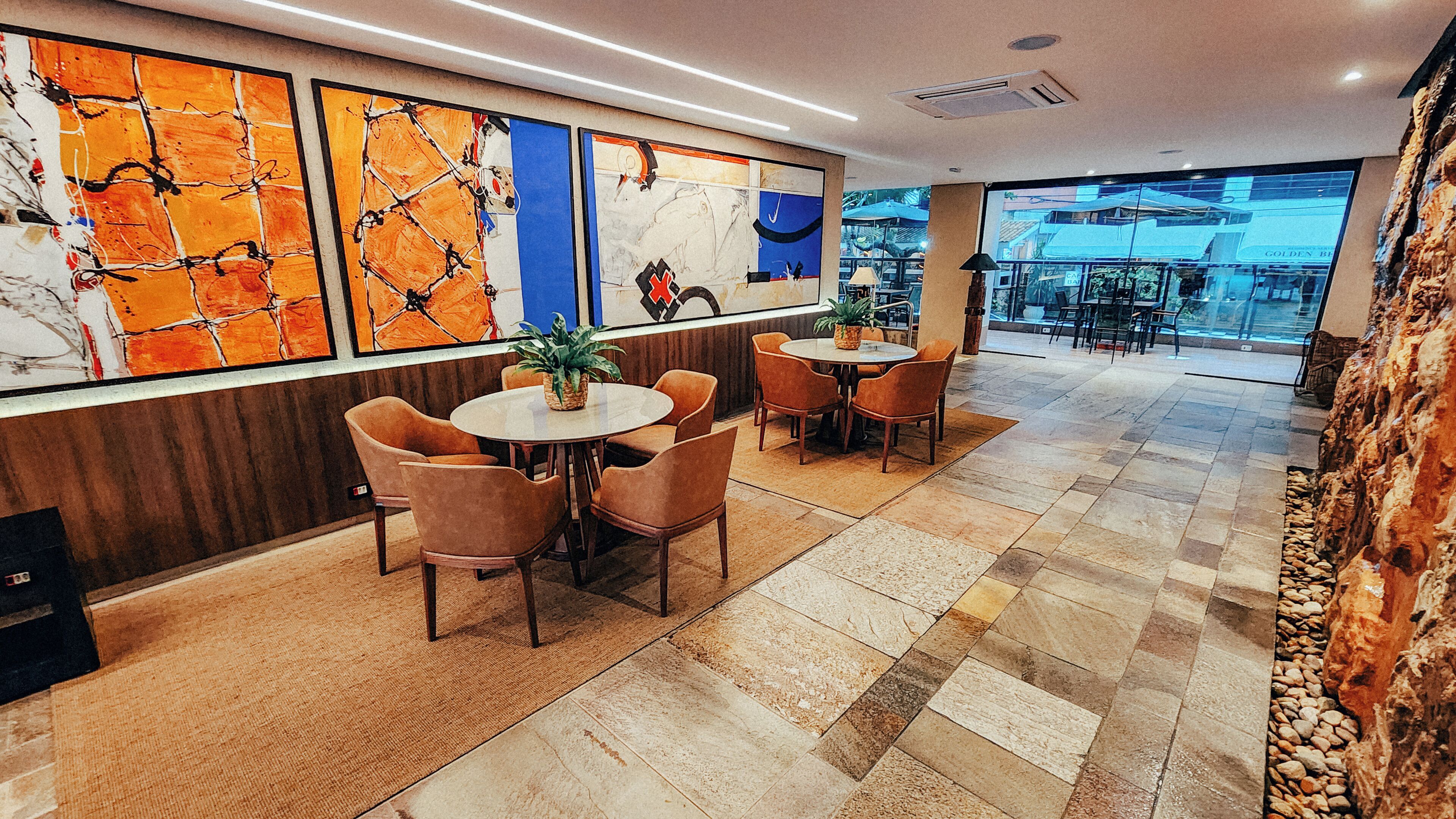 A modern interior with a bar area, seating with round tables, and abstract art on the walls.