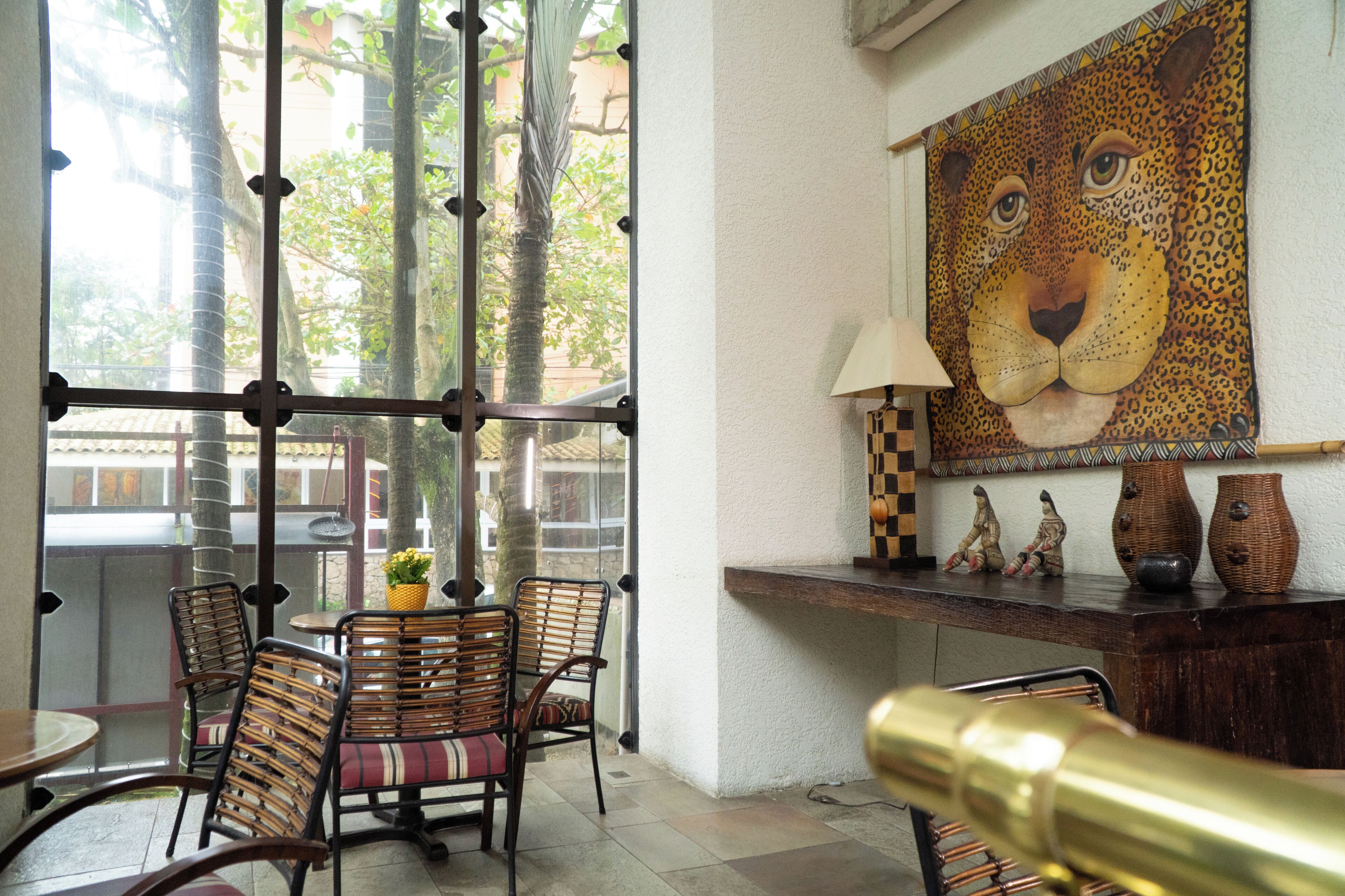 A room with wicker chairs, a table with a plant, a leopard painting, and decorative vases.