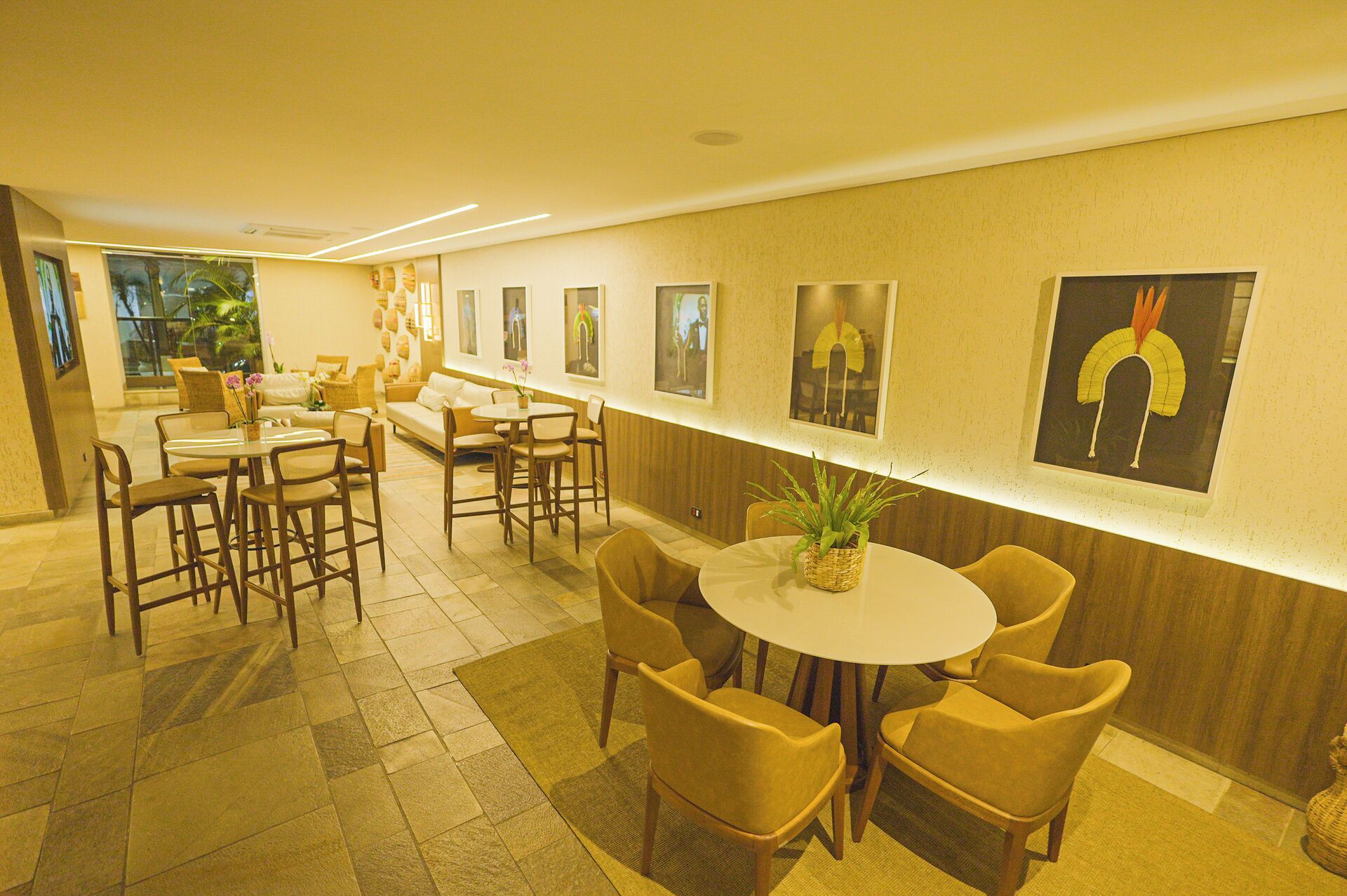 A modern hotel lobby with a long reception desk, comfortable seating areas, and artwork on the walls.