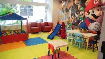 Un espace de jeux pour enfants avec une piscine à balles, des toboggans et une fresque murale sur le thème de Mario.