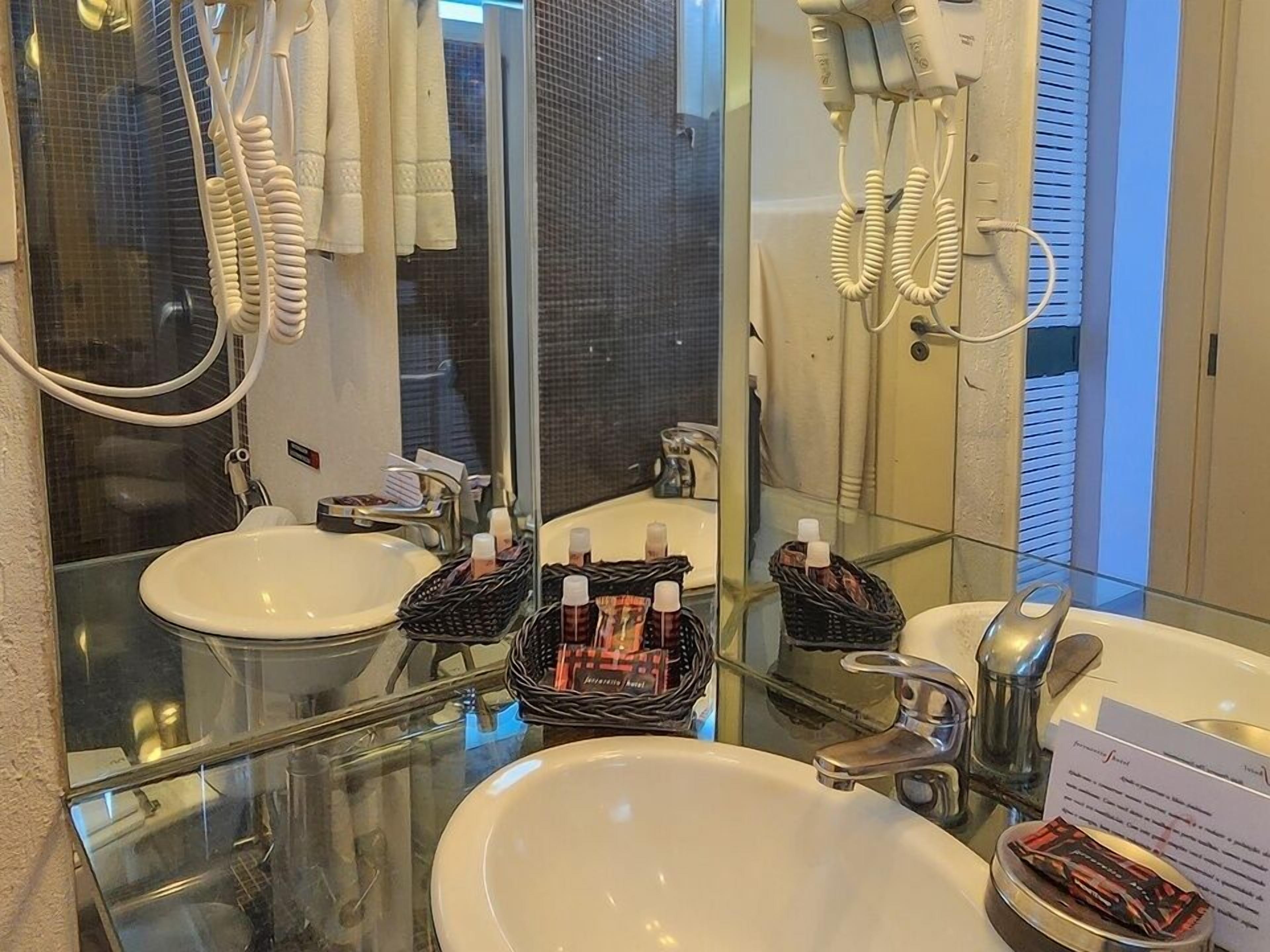 Un baño con dos lavamanos, cabina de ducha de vidrio y un secador de pelo montado en la pared.