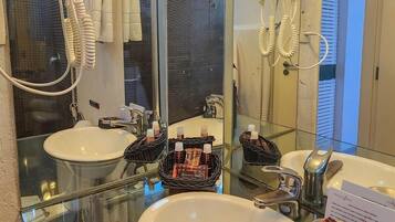 Un baño con dos lavamanos, cabina de ducha de vidrio y un secador de pelo montado en la pared.