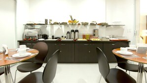A modern kitchen with a buffet setup, including a coffee machine, fruit, and various food items. - Pousada Ecomaceio (Maceió)