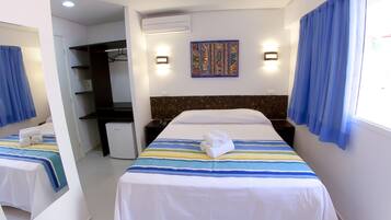 A hotel room with two beds, a desk, a wardrobe, and a small kitchenette.