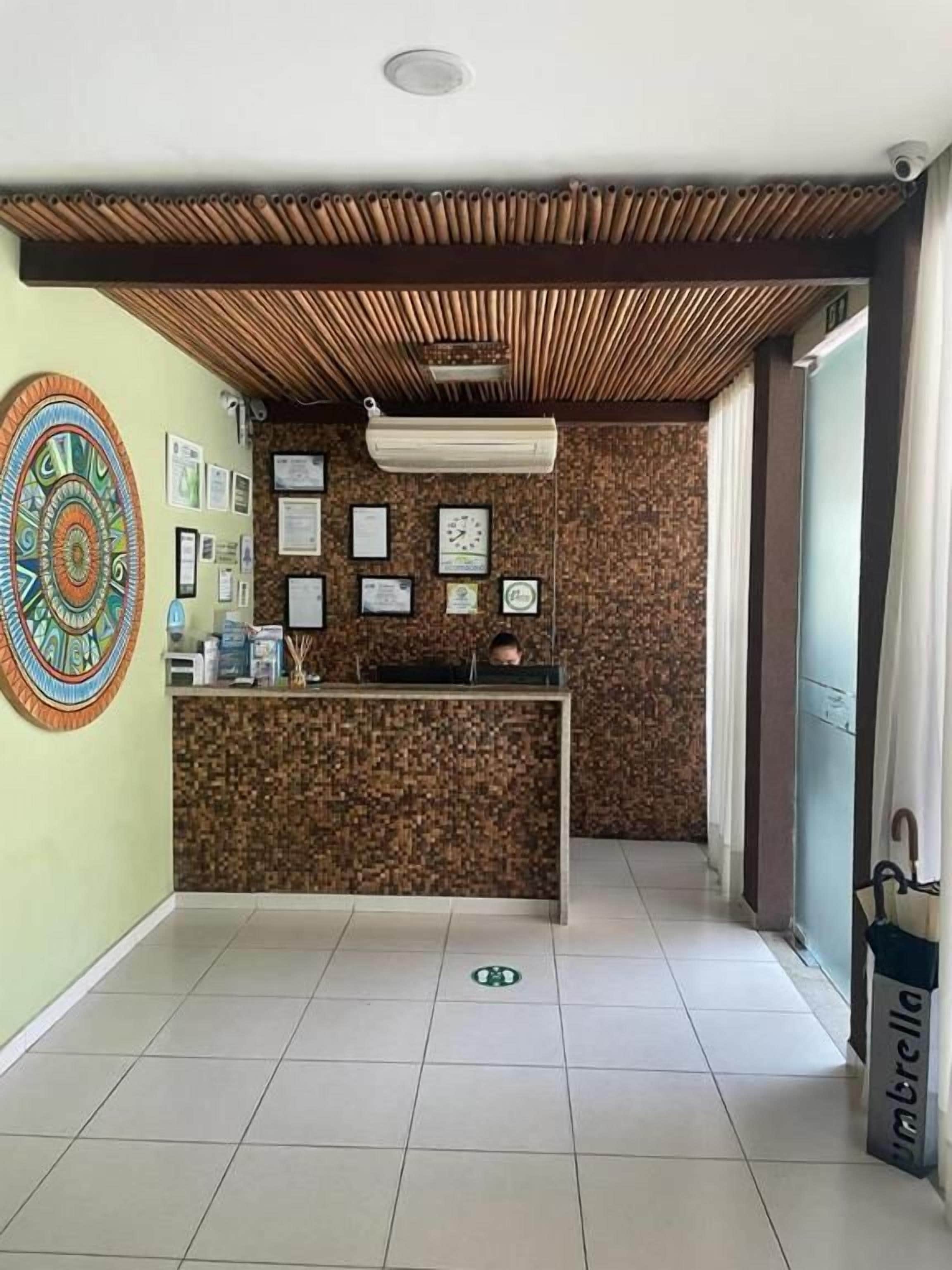 A reception area with a reception desk, framed certificates, and a decorative wall piece.