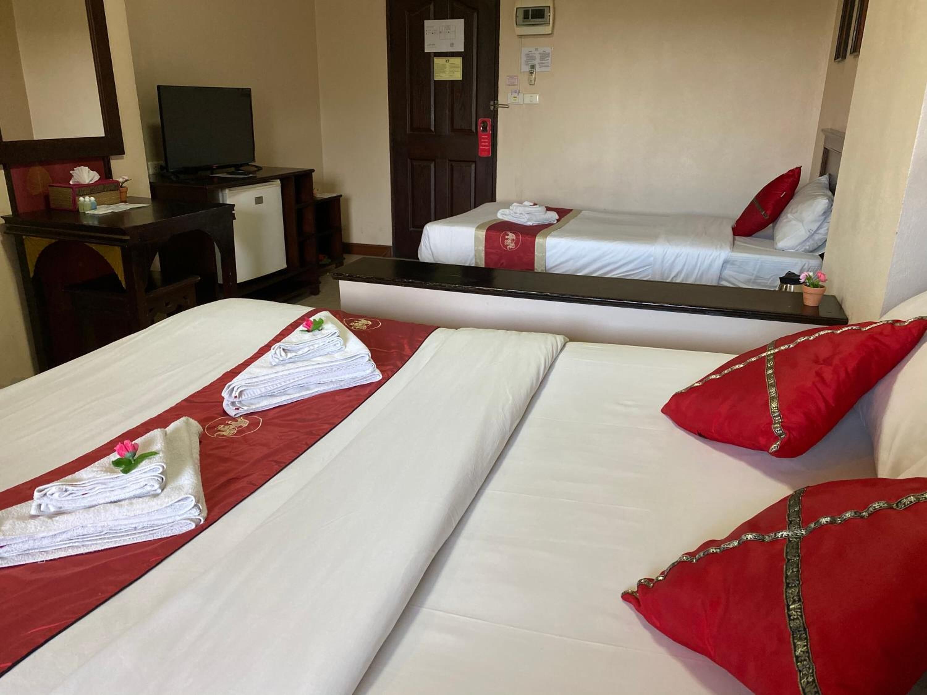 A hotel room with two beds, a desk with a television, and a mirror.
