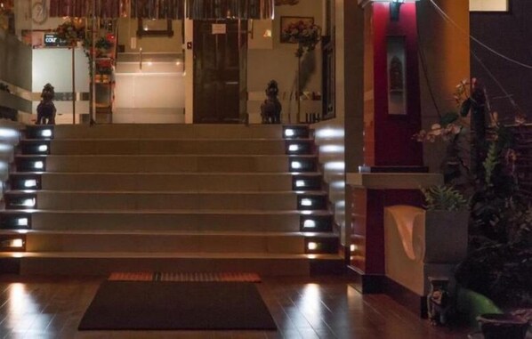 Un vestíbulo de hotel con una imponente escalera, un mostrador de recepción y una zona de recepción.