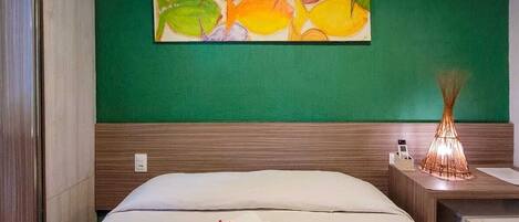 Ein Hotelzimmer mit einem Bett, einer grünen Wand und einem Bild von Fischen.