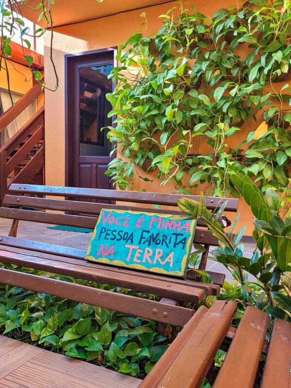 A wooden bench with a sign that reads "VOCÊ É MINHA PESSOA FAVORITA NA TERRA" in Portuguese.