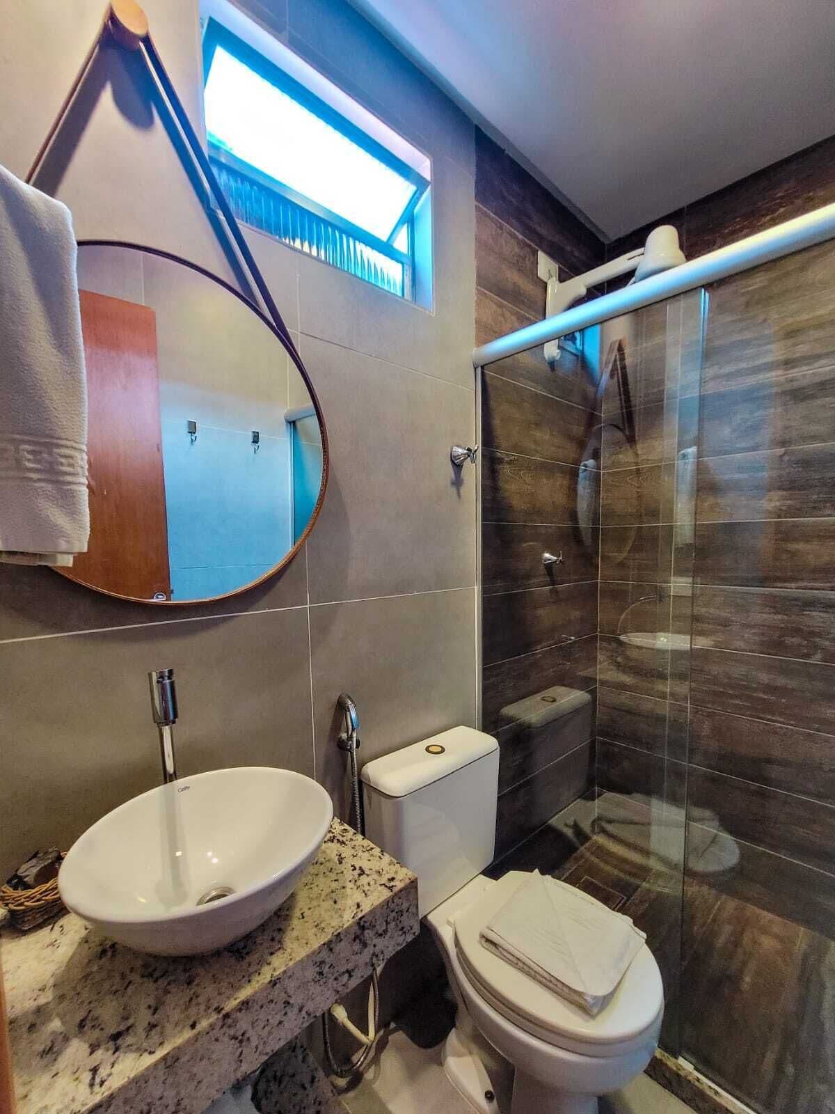 A modern bathroom with a round sink, a toilet, and a glass shower enclosure.
