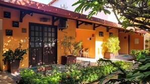 A courtyard with a wooden pergola, potted plants, and a small seating area. - Pousada Casamar (Ipojuca)