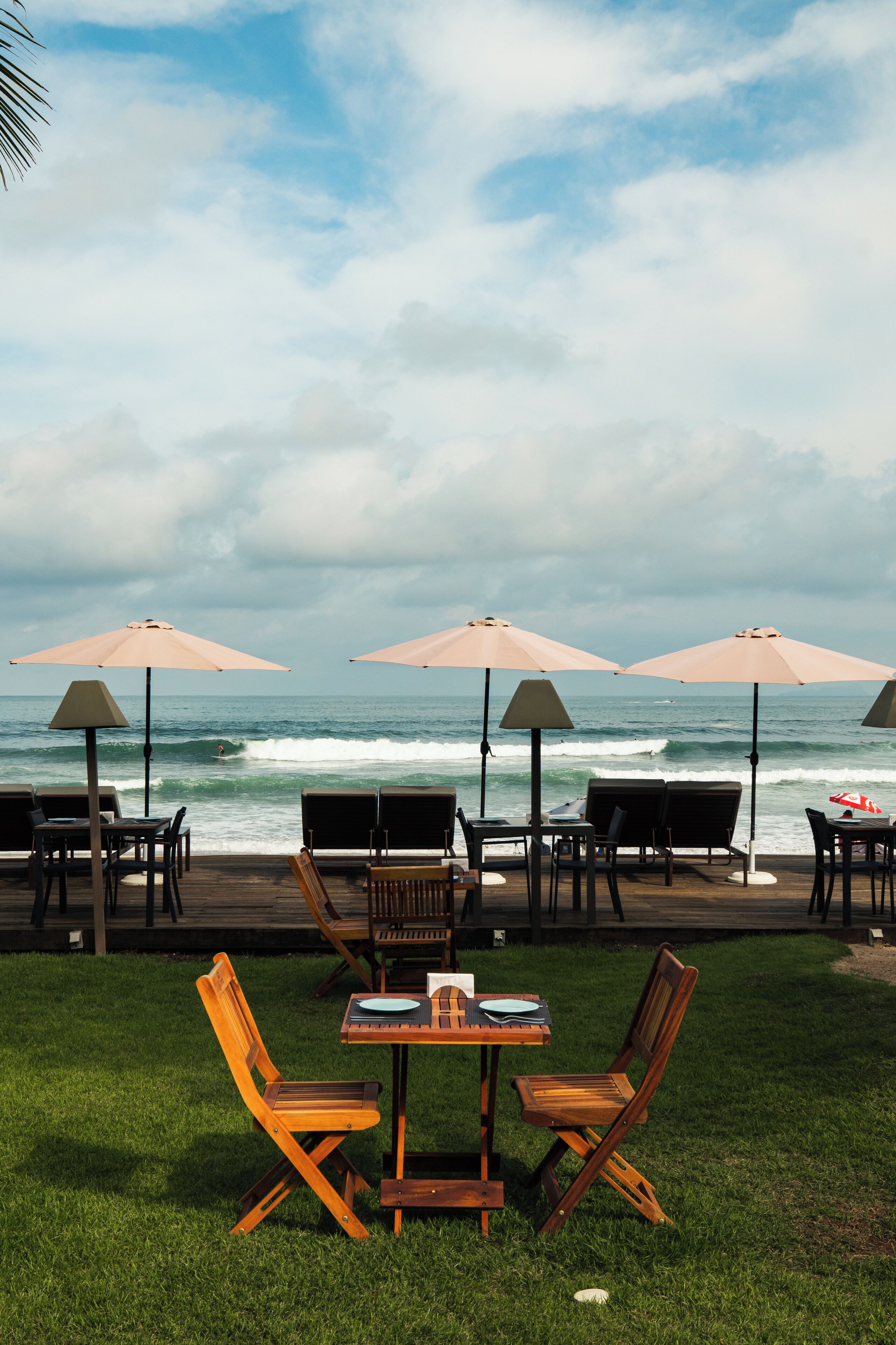 A deck with outdoor seating and umbrellas overlooking the ocean.