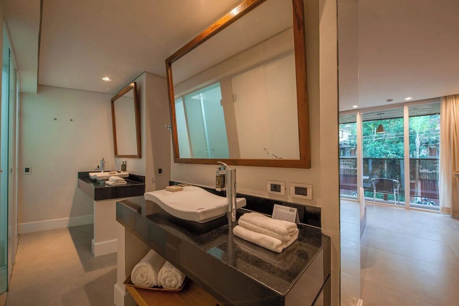 A modern bathroom with two sinks, large mirrors, and a glass shower enclosure.