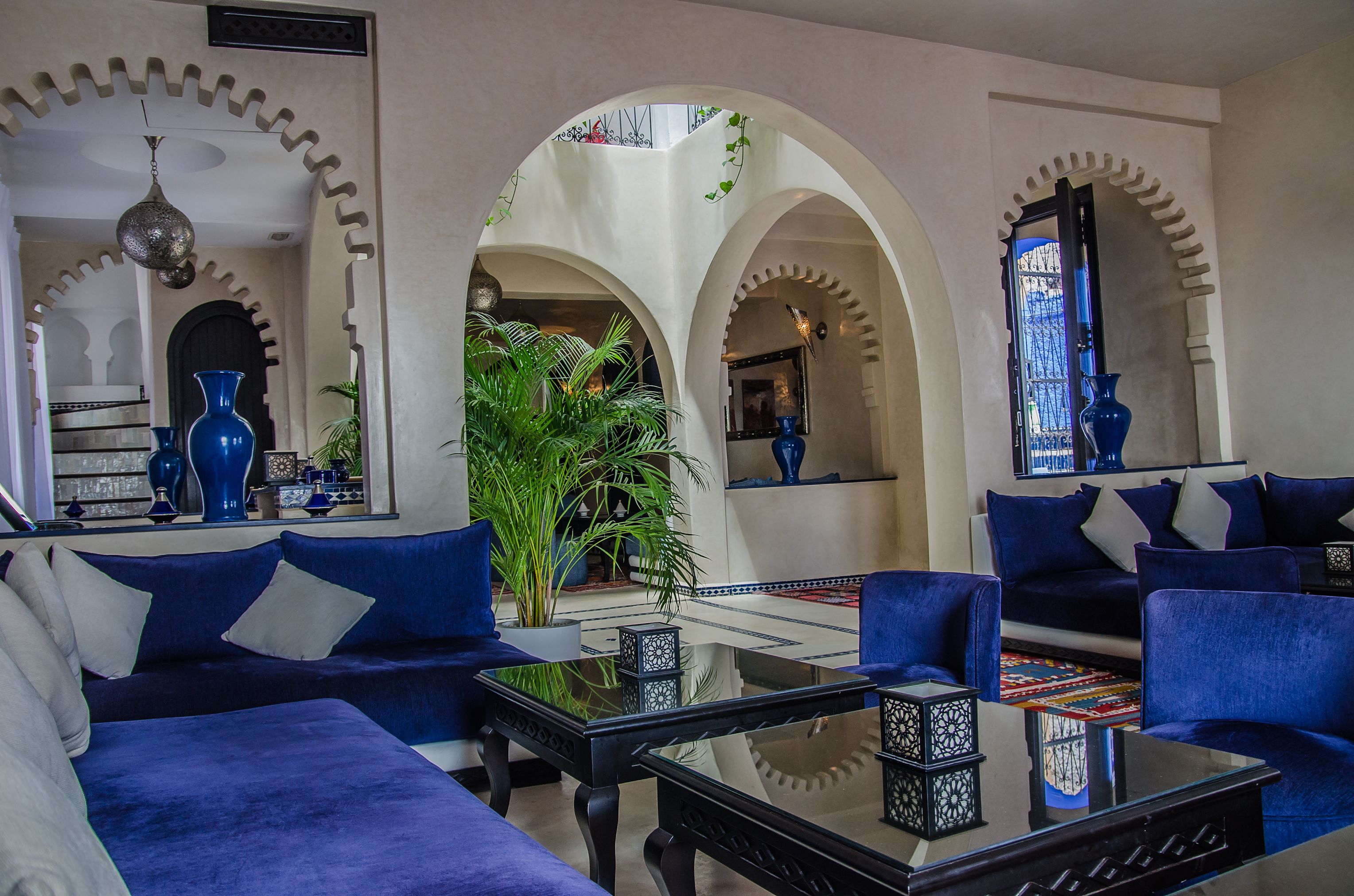 A living room with blue sofas, a coffee table, and a large mirror.