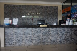 A reception desk with a stone wall backdrop, a sign for 'Amara Motel Langkawi', and a 'Reception' sign. - Amara Motel (Langkawi)
