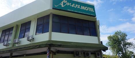A two-story building with a sign reading "Amara Motel" and air conditioning units on the facade.