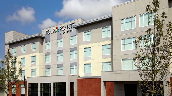 Un edificio de hotel de varios pisos con un cartel que dice "FOUR POINTS BY SHERATON".