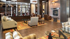 A modern lounge area with leather sofas, a fireplace, and a variety of decorative items on shelves. - Four Points by Sheraton Edmonton International Airport (Nisku)