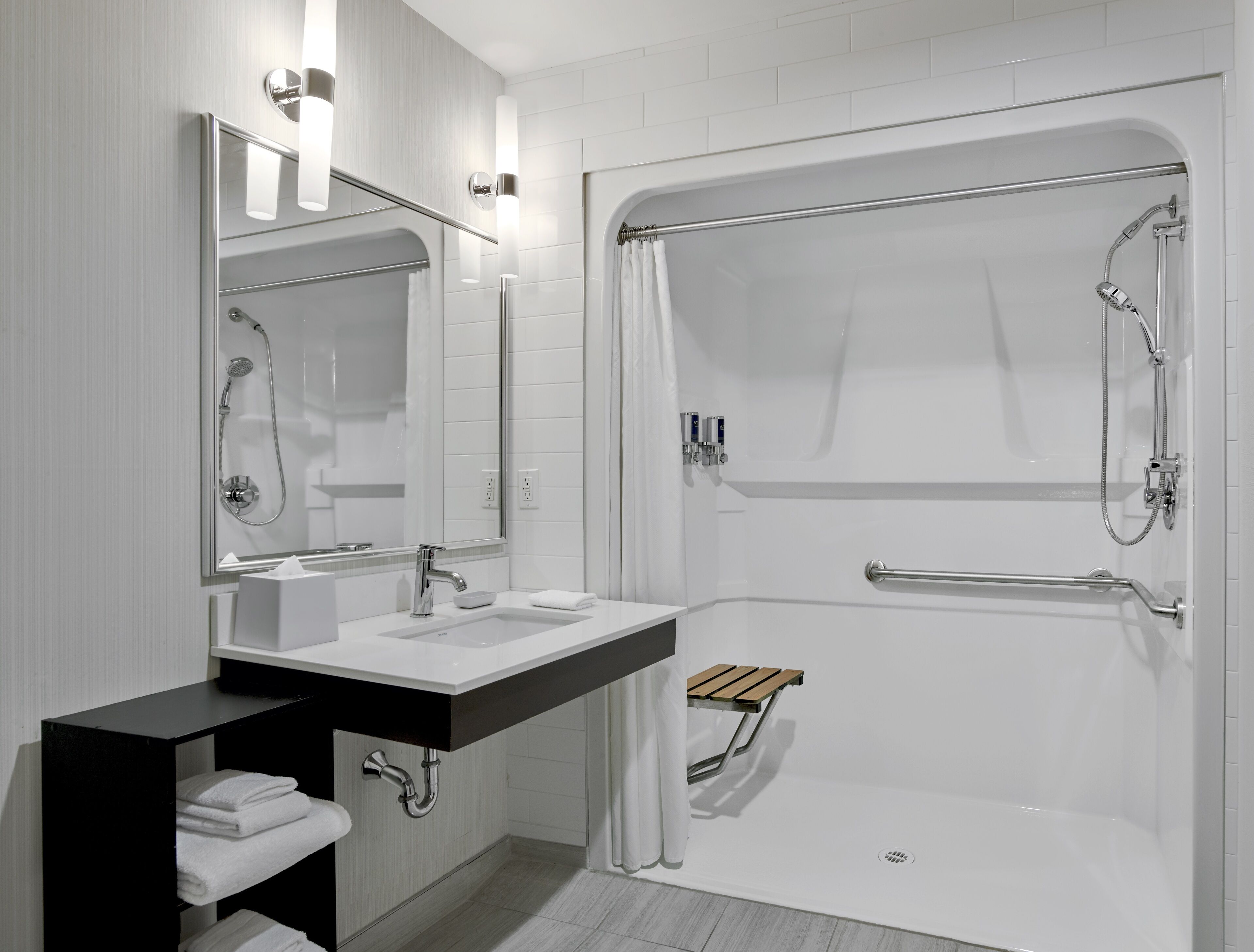 A modern bathroom with a white sink, mirror, and shower.