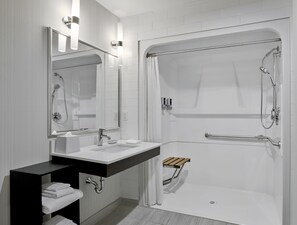 Un baño moderno con lavamanos, espejo y ducha blancos.