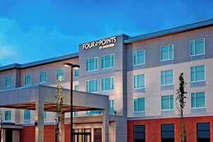 Un hotel de varios pisos con una fachada moderna, amplias ventanas y señalización destacada de 'FOUR POINTS BY SHERATON'.