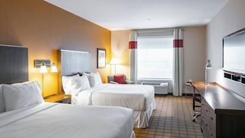 A hotel room with two beds, a desk, a chair, a TV, and a window with curtains.