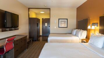 A hotel room with two beds, a desk with a chair, a television, and a framed picture on the wall.