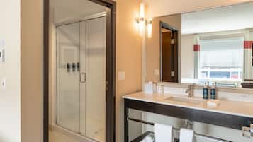 A modern bathroom with a glass shower enclosure, a dark wooden vanity, and a large mirror.