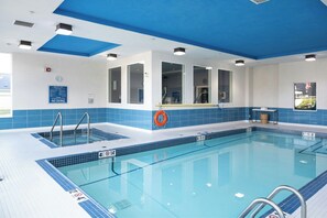 A swimming pool with clear water, marked depth lines, and safety signs. - Four Points by Sheraton Edmonton International Airport (Nisku)