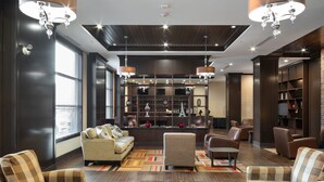 A modern lobby with a sofa, armchairs, a glass coffee table, a fireplace, and a bookshelf. - Four Points by Sheraton Edmonton International Airport (Nisku)