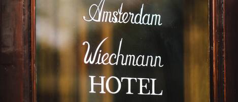 A hotel sign with the name "Amsterdam Wiechmann HOTEL" in a classic font.